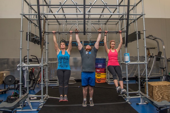 Stefanie Tucker, Steven Tucker, and Jamie Knight perform pull-ups on the newly installed Alpha Warrior Battle Rig Feb. 26, 2018, at Scott Air Force Base, Ill. The battle rig encompasses the four pillars of Comprehensive Airmen Fitness: physical, social, spiritual and mental fitness. (U.S. Air Force photo by Senior Airman Melissa Estevez)