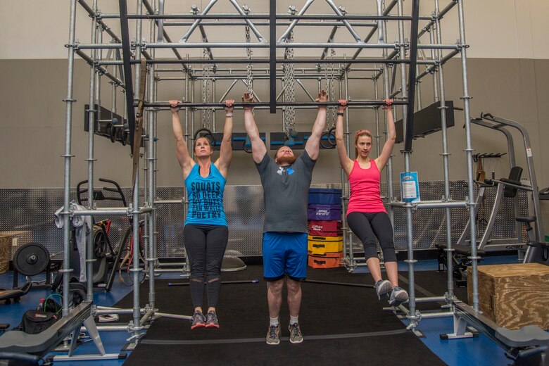 Stefanie Tucker, Steven Tucker, and Jamie Knight perform pull-ups on the newly installed Alpha Warrior Battle Rig Feb. 26, 2018, at Scott Air Force Base, Ill. The battle rig encompasses the four pillars of Comprehensive Airmen Fitness: physical, social, spiritual and mental fitness. (U.S. Air Force photo by Senior Airman Melissa Estevez)
