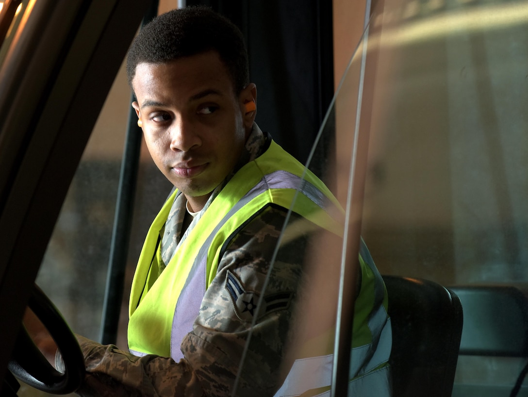 U.S. Air Force Airman 1st Class Daniel Johnson, 100th Logistics Readiness Squadron traffic management officer, checks to make sure the area is clear before reversing his forklift during a cargo deployment function at RAF Mildenhall, England, March 9, 2018. The CDF involved moving almost 10,000 pounds of equipment to Camp Lemonier, Djibouti. (U.S. Air Force photo by Airman 1st Class Benjamin Cooper)