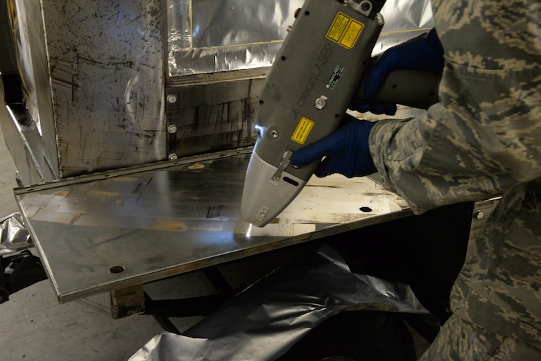 Airman 1st Class Levi Gordon, 60th Maintenance Squadron aircraft structural maintenance, uses a Clean Laser 1000 to remove paint from a sheet of metal March 7 at Travis Air Force Base, California. The 1000-watt laser can remove paint and corrosion. It reduces the waste created from sanding paint by 90 percent Travis was chosen as one of two bases to test the capabilities of the laser. (U.S. Air Force photos by Staff Sgt. Amber Carter)