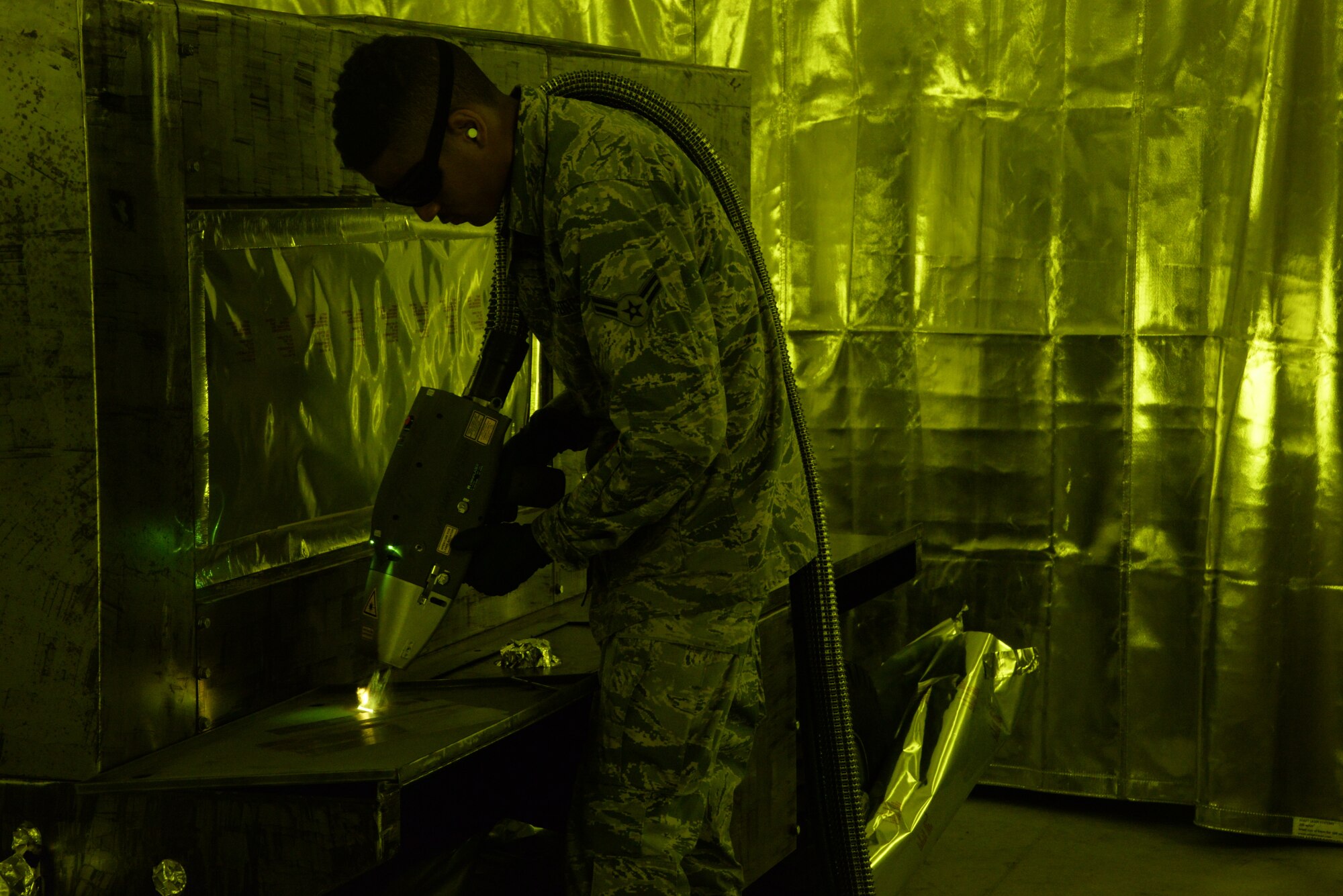 Airman 1st Class Levi Gordon, 60th Maintenance Squadron aircraft structural maintenance, uses a Clean Laser 1000 to remove paint from a sheet of metal March 7 at Travis Air Force Base, California. The 1000-watt laser can remove paint and corrosion. It reduces the waste created from sanding paint by 90 percent Travis was chosen as one of two bases to test the capabilities of the laser. (U.S. Air Force photos by Staff Sgt. Amber Carter)