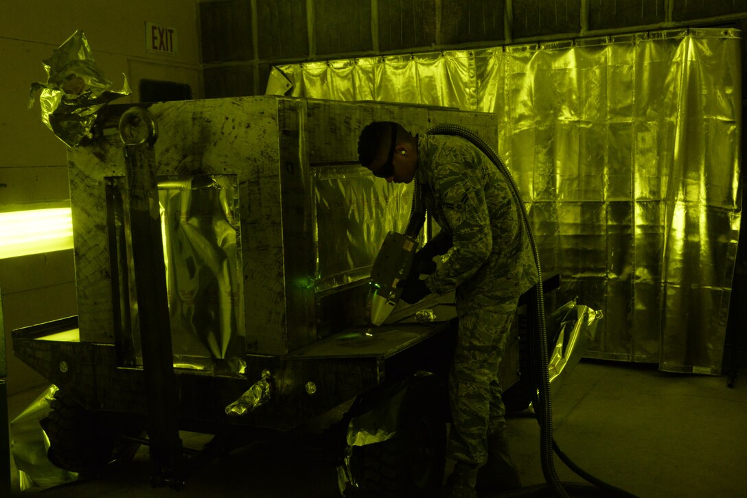 Airman 1st Class Levi Gordon, 60th Maintenance Squadron aircraft structural maintenance, uses a Clean Laser 1000 to remove paint from a sheet of metal March 7 at Travis Air Force Base, California. The 1000-watt laser can remove paint and corrosion. It reduces the waste created from sanding paint by 90 percent Travis was chosen as one of two bases to test the capabilities of the laser. (U.S. Air Force photos by Staff Sgt. Amber Carter)