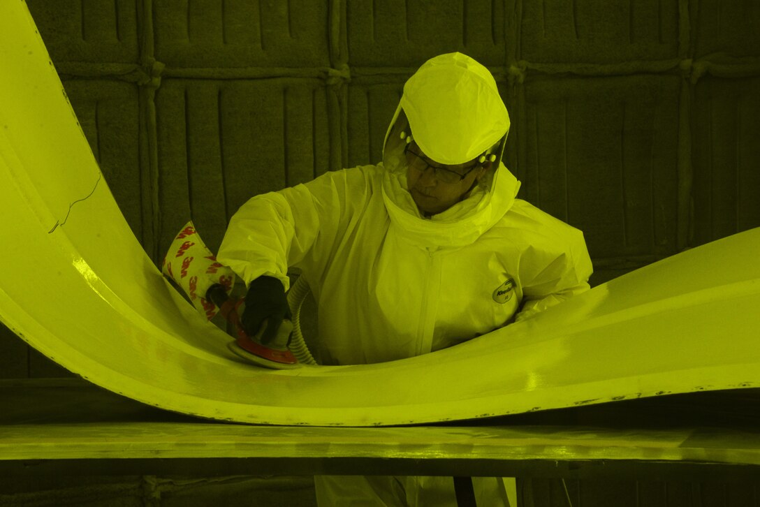 Kathy Fruits, 60th Maintenance Squadron aircraft structural maintenance, uses a sander to remove paint March 7 at Travis Air Force Base, Calif. The suit is completely air sealed and hooked up to oxygen in order to protect her from harmful paint chemicals that are released during the sanding process. The suit is not needed while using the Clean Laser due to the reduction of sawdust and airborn debris. (U.S. Air Force photo by Staff Sgt. Amber Carter)