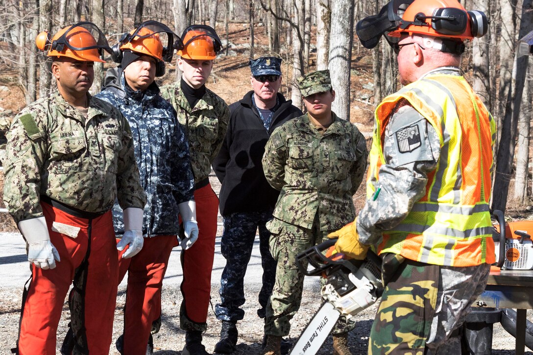 A soldier briefs troops on using a chainsaw safely.