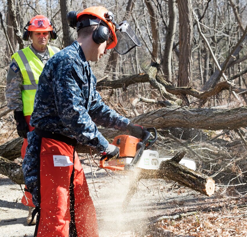 A sailor practices operating a chainsaw.