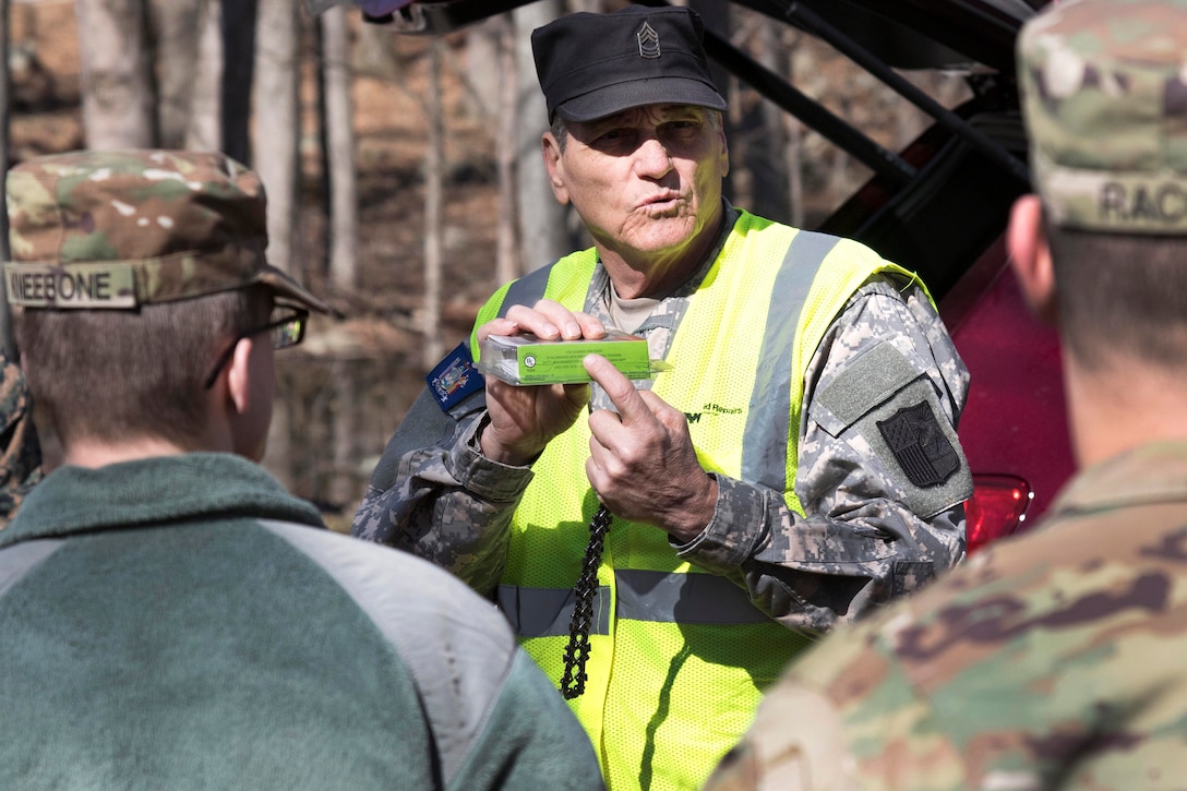 A soldier briefs troops on chainsaw operations and safety.