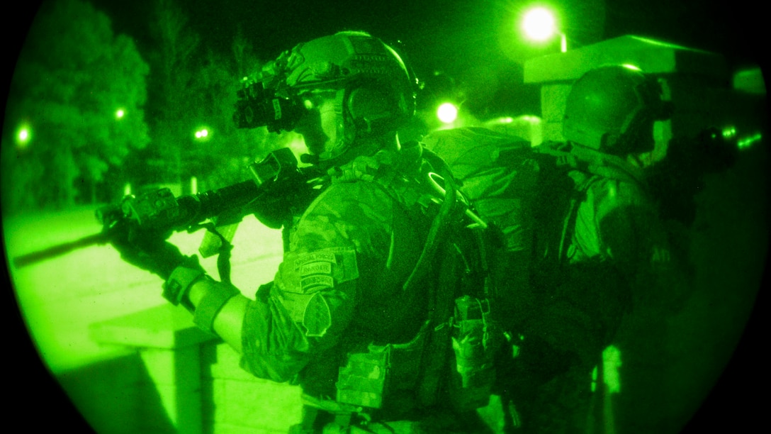 As seen through a green light, soldiers train during an exercise at night.