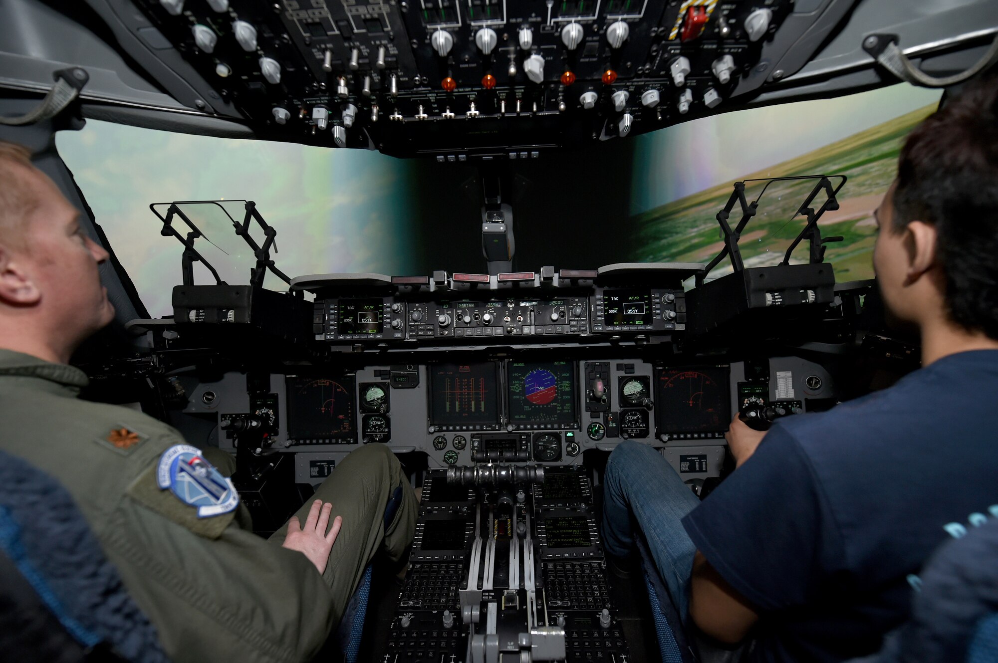 U.S. Air Force Maj Jon Paul Griffin, a C-17 Globemaster III flight training instructor assigned to the 730 Air Mobility Training Squadron, flies a simulator with a civilian pilot in training, March 10, 2018, at Altus Air Force Base, Okla.