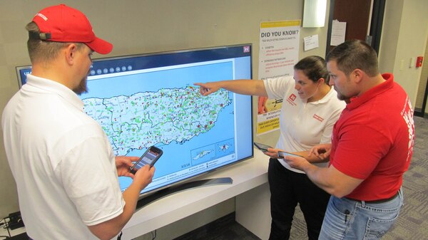 U.S. Army Corps of Engineers employees Bill Spring, (left) Jake Ellison, (middle) and Kara Hickey, Geographic Information Systems Analyst and mission liaisons for the Task Force Temporary Emergency Power Team discuss issues as they fine-tune an app that was created by the team on March 2, 2018 in San Juan Puerto Rico.  The app tracks approving official signatures and checklist of commissioned and decommissioned micro grids.