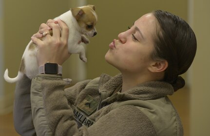 U.S. Army Pvt. Aeris Makley, Public Health Activity, Fort Gordon, animal care specialist, shows compassion to a puppy visiting the Veterinarian Clinic here March 9, 2018.