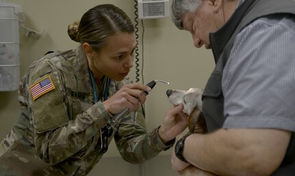 U.S. Army Capt. Chelsi Deaner, left, Public Health Activity, Fort Gordon, veterinarian core officer, uses a light to perform a check on a dog’s eyes at the veterinarian clinic here March 9, 2018.