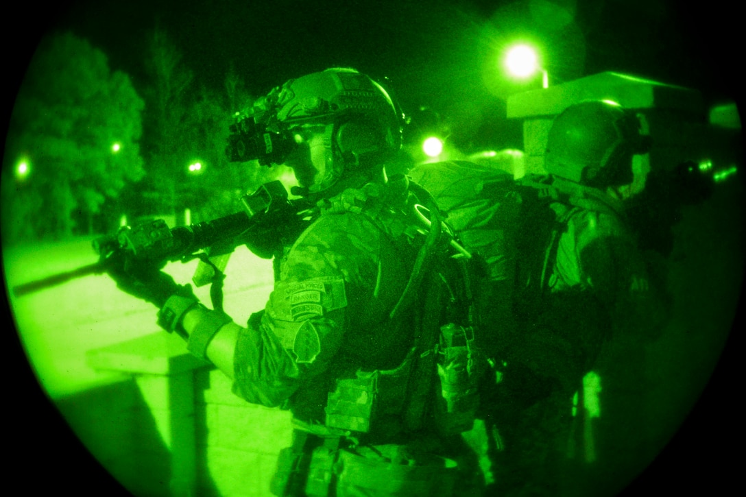 As seen through a green light, soldiers train during an exercise at night.