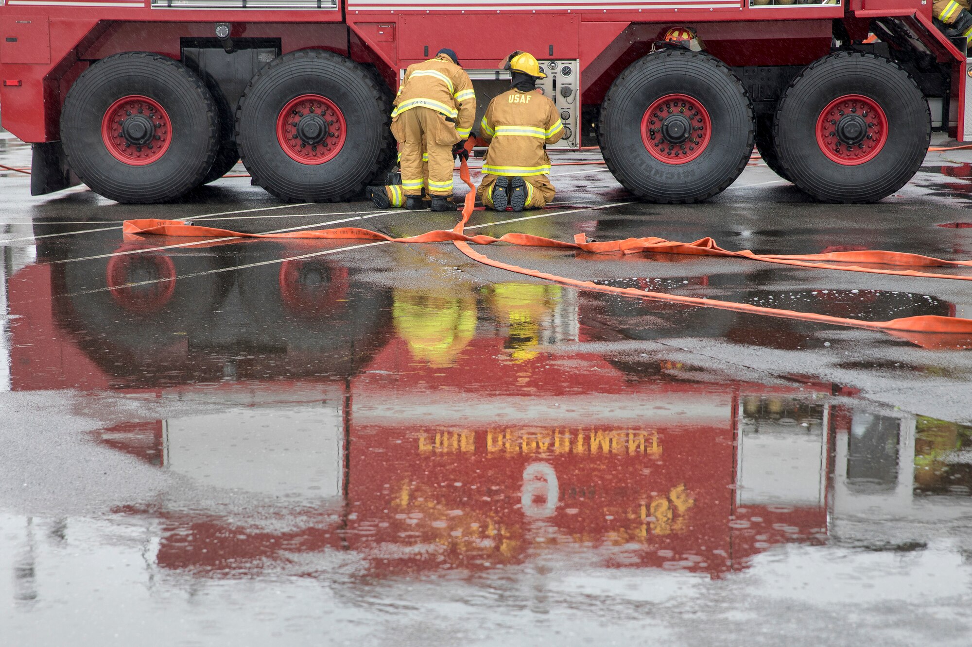 Firefighters assigned to the 374th Civil Engineer Squadron pack away hoses after conducting a simulated aircraft fire drill at Yokota Air Base, Japan