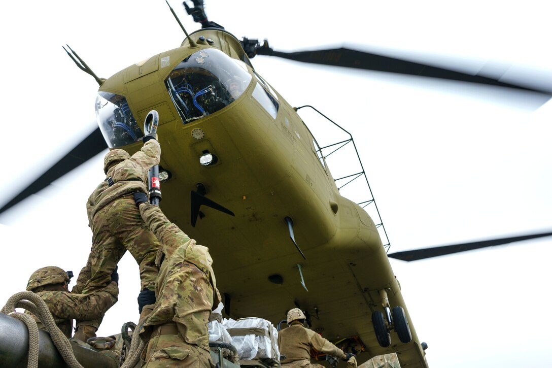 Soldiers prepare to hook a M777 howitzer to a CH-47 Chinook helicopter.