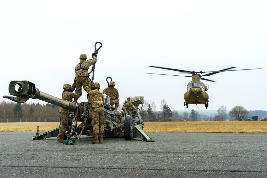 Soldiers prepare to hook a M777 howitzer to a CH-47 Chinook.