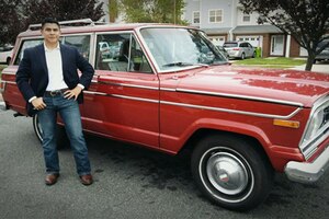 A Marine stands next to a red Jeep Wagoneer.