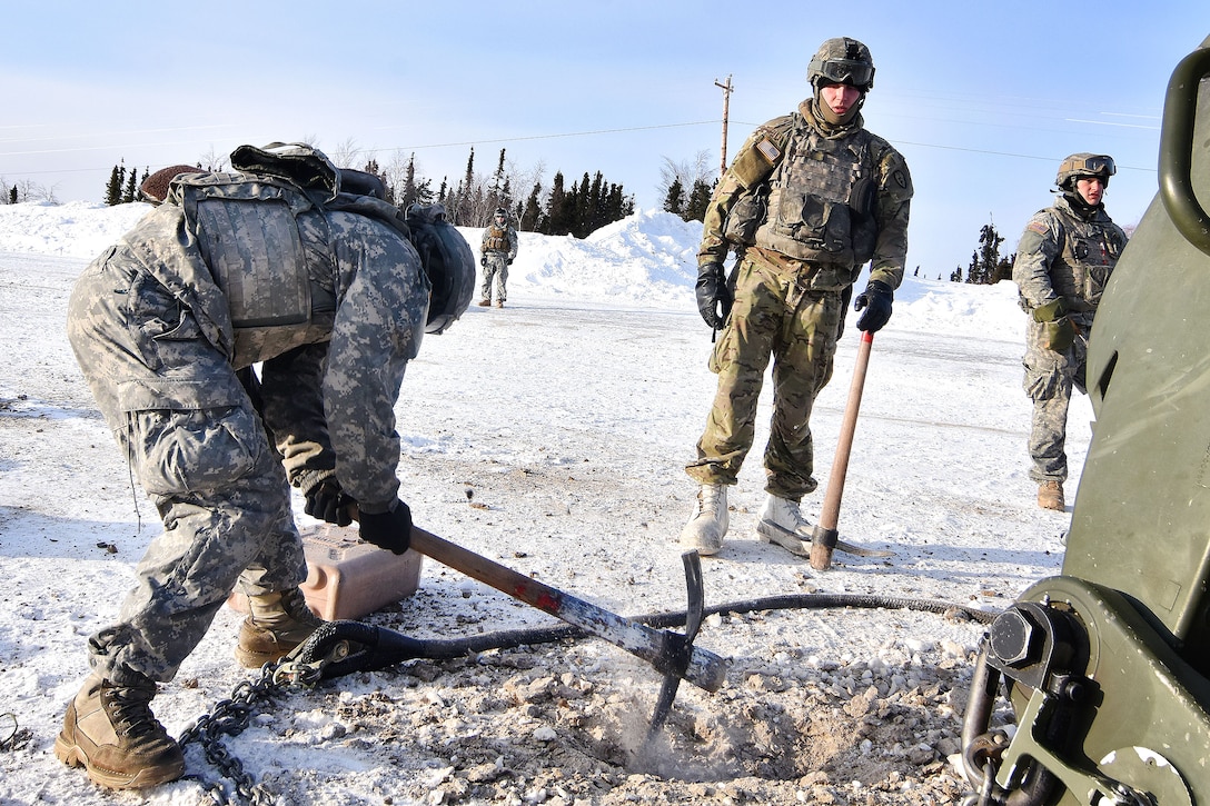 Soldiers use pickaxes to dig through the frozen ground.