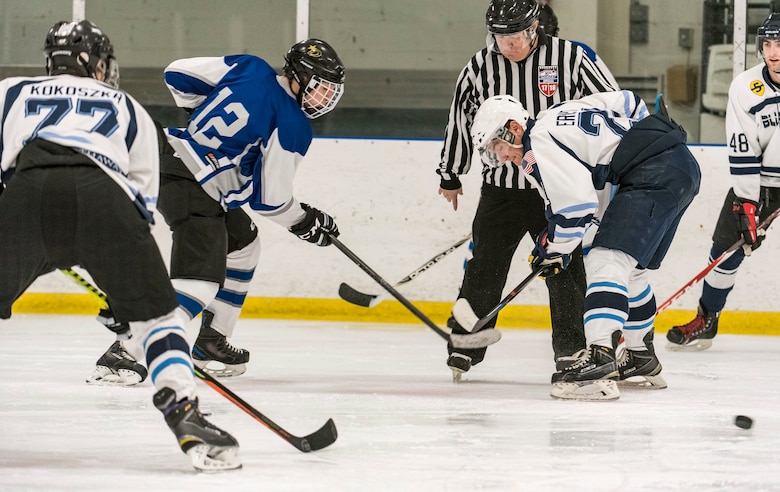 Dover Eagles center Sam Ernst (21) and Dover Fraternal Order of Police Lodge 15 forward Steven Schultz (12), face off during a charity hockey game March 10, 2018, at the Centre Ice Rink in Harrington, Del. The Eagles won the game 8-4, making it two years in a row they have won. (U.S. Air Force photo by Roland Balik)