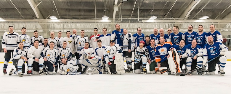 The Dover Eagles and Dover Fraternal Order of Police Lodge 15 hockey teams pose for a group photo after a charity hockey game March 10, 2018, at the Centre Ice Rink in Harrington, Del. The proceeds of the game went to the families of Correctional Officer Lt. Steven Floyd, who was killed in the line of duty, and Dover Police Department officer Cpl. Thomas Hannon, who passed away due to medical complications he suffered from a line of duty injury. (U.S. Air Force photo by Roland Balik)