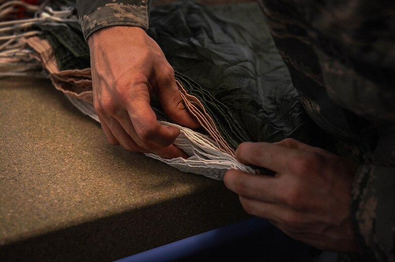 U.S. Air Force Senior Airman Ryan Loparo, 20th Equipment Maintenance Squadron aircrew flight equipment (AFE) journeyman, lines up the edges of a parachute at Shaw Air Force Base, S.C., March 5, 2018.