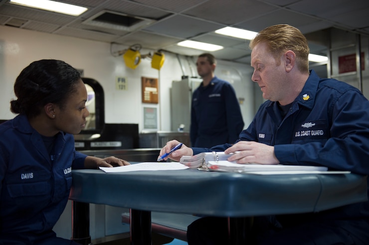 A Coast Guard yeoman assists a fellow Coast Guardsman, Feb. 6, 2013, aboard the Coast Guard Cutter Forward.