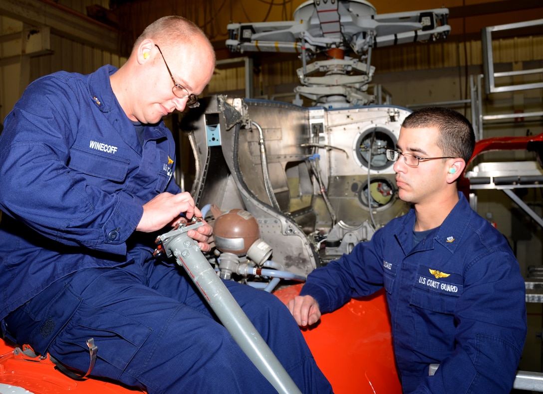 Petty Officer 3rd Class Robert N. Winecoff, of Smyrna, Tenn., (left), a student at the Coast Guard's Aviation Technical Training Center, inspects the tail rotor drive shaft on an MH-65 helicopter with fellow aviation maintenance technician Petty Officer 3rd Class Danny S. Gonzalez, of Tampa, Fla., March 18, 2014.