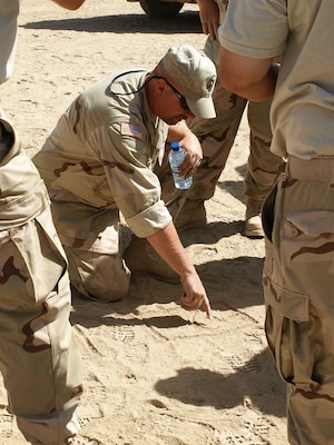 Carl Houdeshell, a member of the deployable depot at DLA Distribution Susquehanna, Pennsylvania, draws a diagram in the sand depicting the layout of DLA Distribution’s site at Kandahar, Afghanistan, before its construction in 2010.