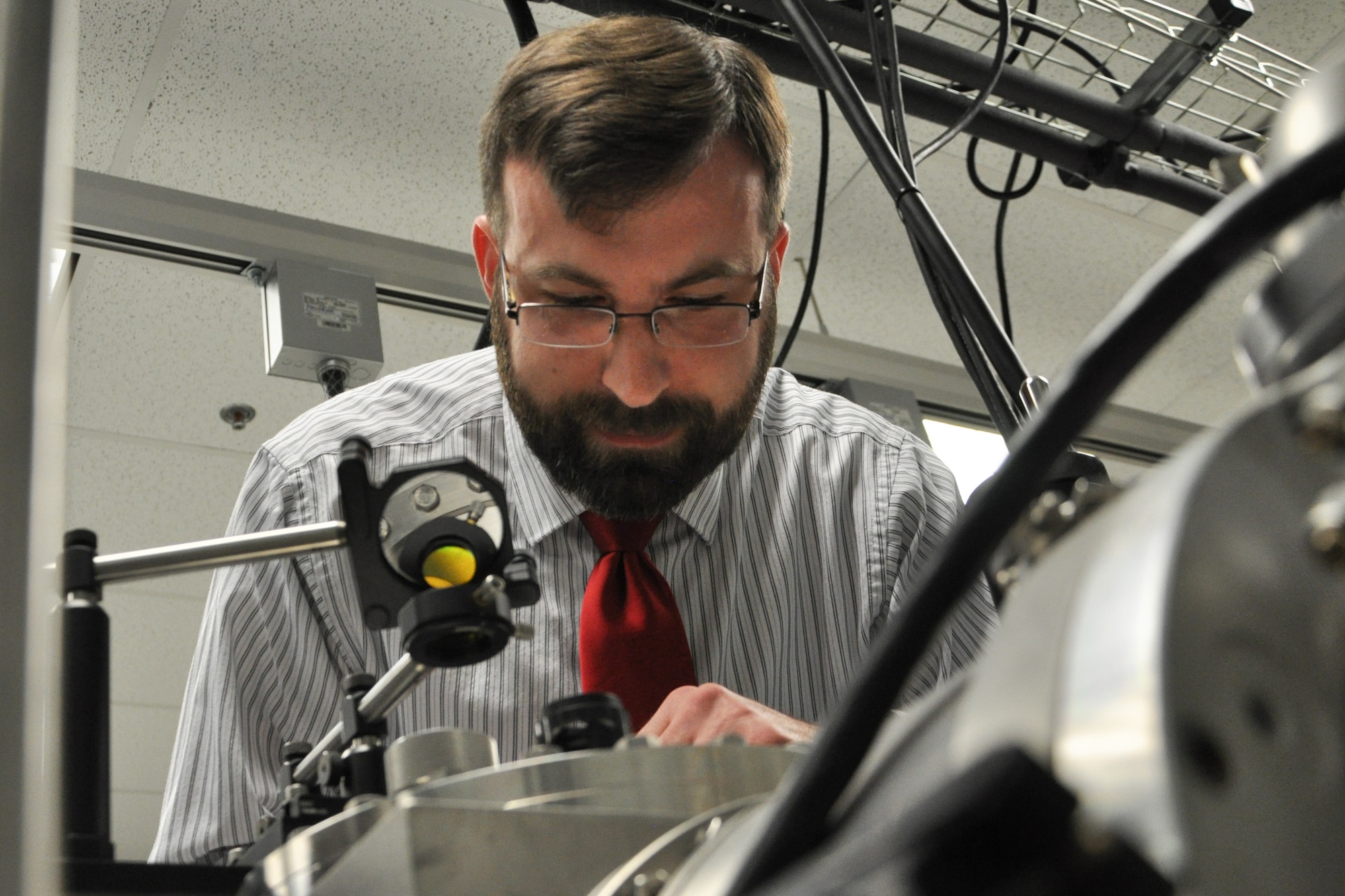 Dr. William Lewis, AFRL Senior Research Chemist with the Turbine Engine Division, Aerospace Systems Directorate, checks the C3 (carbon) evaporation process happening in the Cluster Assembly and Spectroscopy Instrument. (U.S. Air Force Photo/Staff Sgt. Ashley Clingerman)