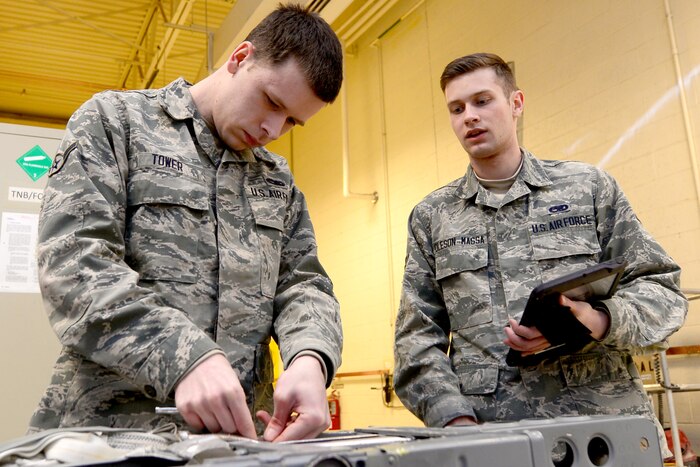 Two airmen work on machinery.