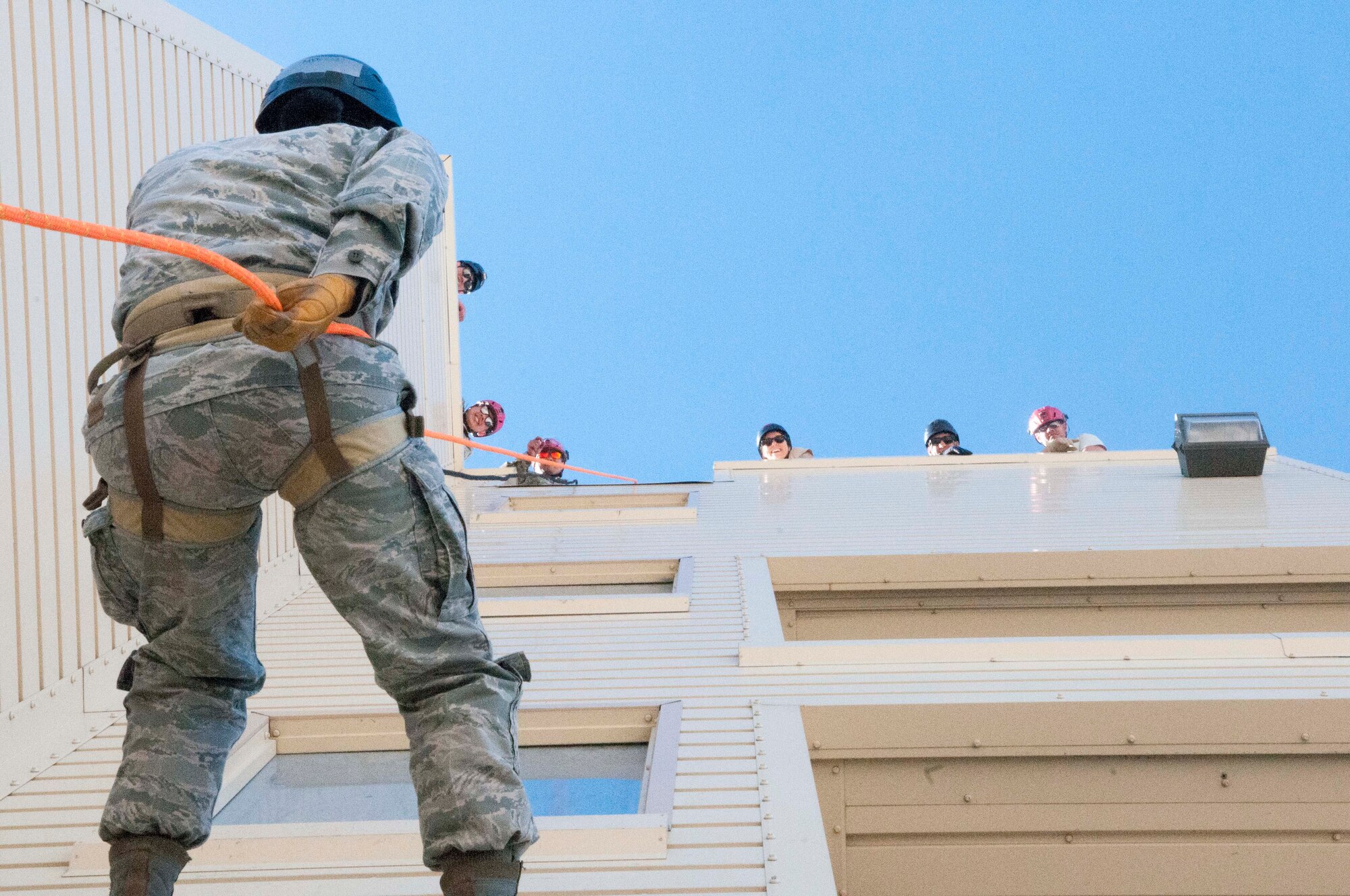 An airman repels down a building while team members look on from above during search and extraction training as part of a Medical Capabilities exercise conducted Jan. 28, 2018 in North Las Vegas.