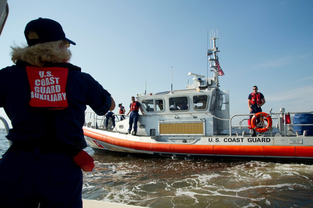 Coast Guard Auxiliary member Dorothy Neiman, with Flotilla 23-03 from Annapolis, Md., greets a passing Coast Guard vessel providing security for an air show during fleet week, Baltimore, Md., Oct. 16, 2016.