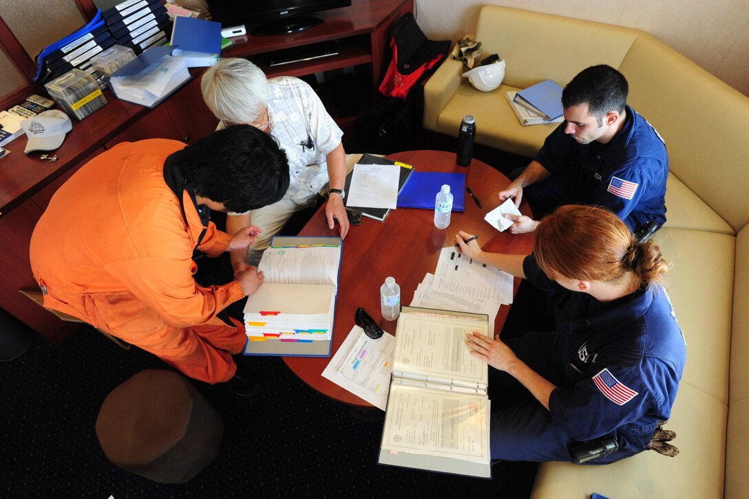 Chief Warrant Officer Dustin Widman and Lt. j.g. Rebecca Grimes review ship logs and records with the captain and first mate aboard the bulk carrier Nikkei Verde at Nine Mile Anchorage on the lower Mississippi River, June 25, 2013.