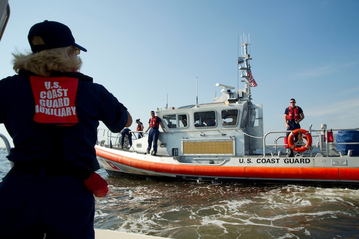 Coast Guard Auxiliary member Dorothy Neiman, with Flotilla 23-03 from Annapolis, Md., greets a passing Coast Guard vessel providing security for an air show during fleet week, Baltimore, Md., Oct. 16, 2016.