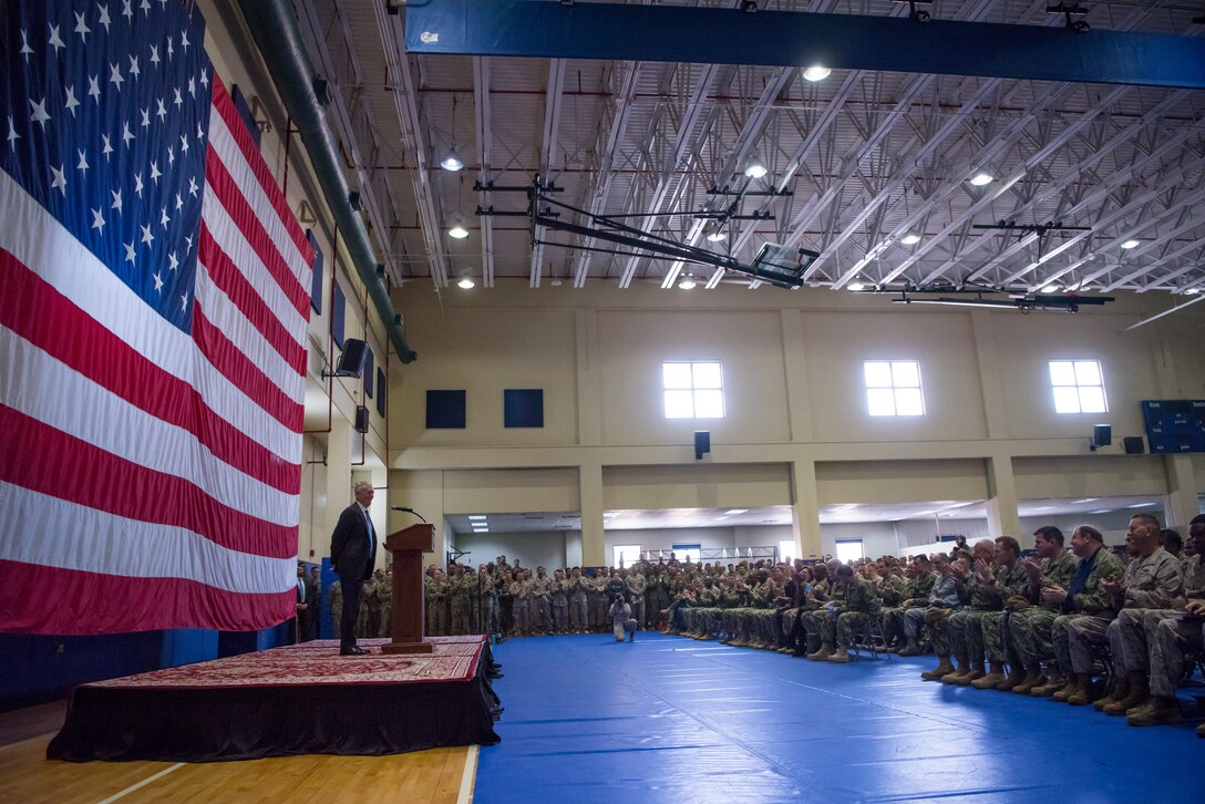 Defense Secretary James N. Mattis stands in front of seated service members.