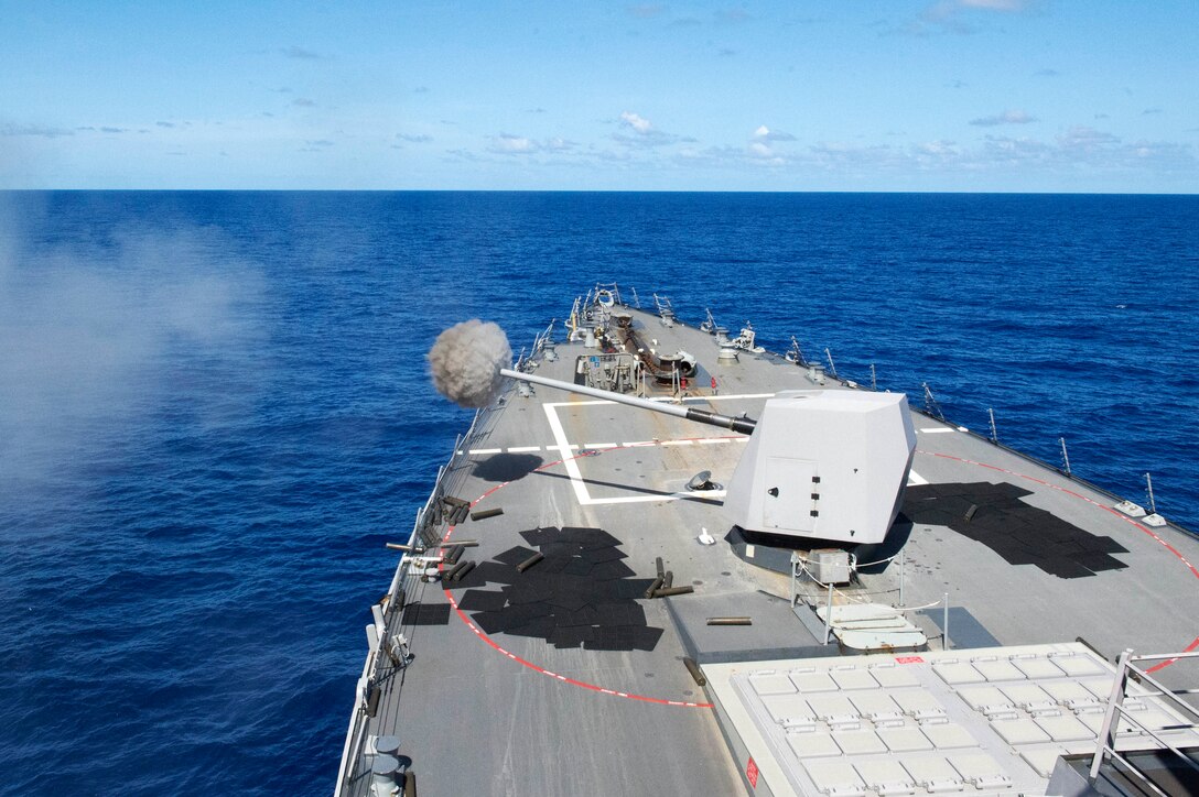 The guided missile destroyer USS Mustin fires its 5-inch gun