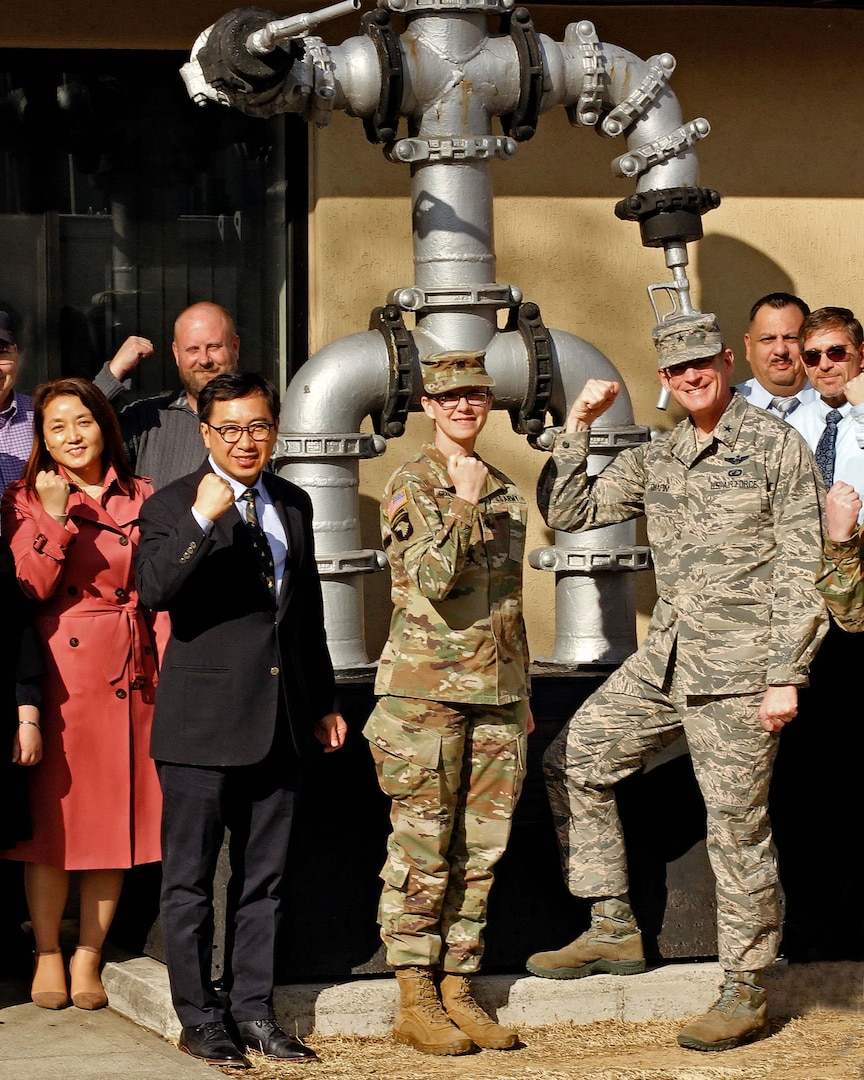 Several members of the DLA Energy Korea team stand in front of a man made from pipeline and petroleum pumping nozzles known as Pipeline Pete.