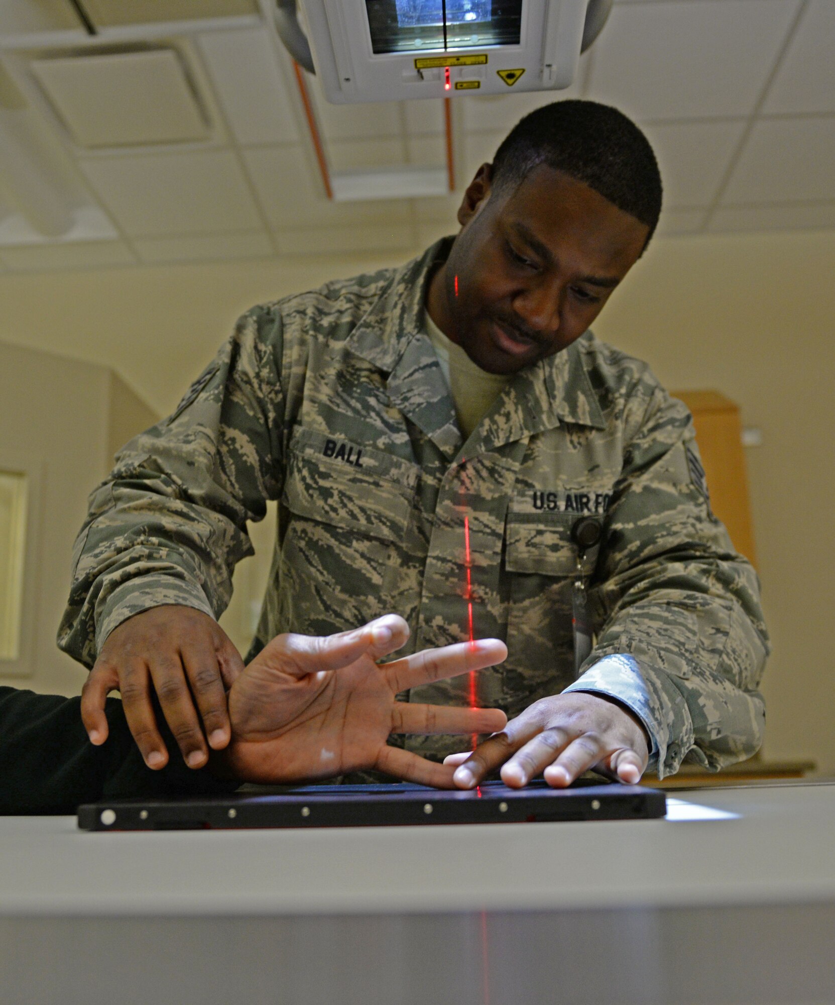 U.S. Air Force Staff Sgt. William Ball adjusts a patient to properly position their hand at Shaw Air Force Base, S.C., March 7, 2018.