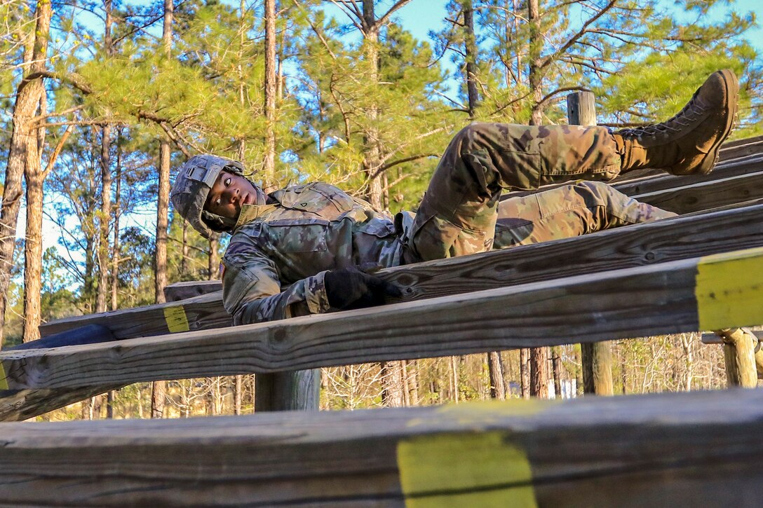 A soldiers weaves in and out of an obstacle with wood planks during a competition.