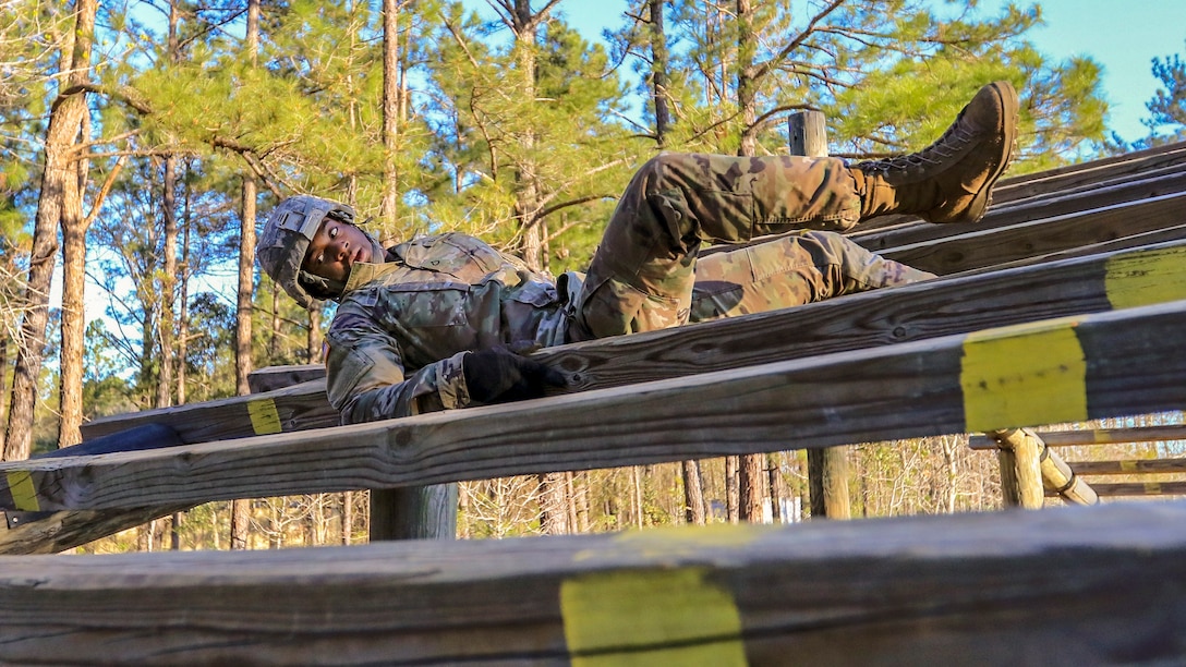 A soldiers weaves in and out of an obstacle with wood planks during a competition.