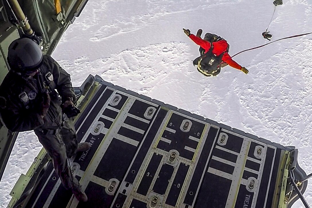 Airmen parachute from an aircraft on to a frozen sea.