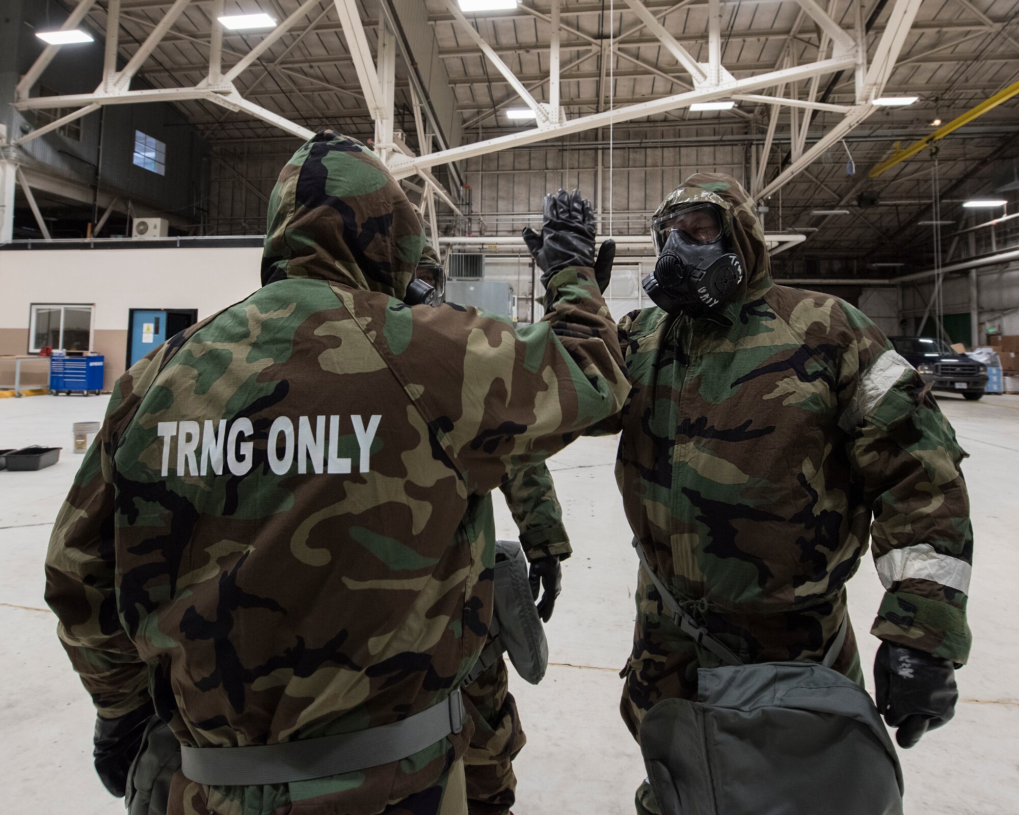 Chaplains Maj. James Whitely and Capt. Stephen Jarman, 141st Air Refueling Wing, high five one another after successfully donning mission-oriented protective posture gear during Chemical, Biological, Radiological, Nuclear Defense training March 6, 2018 at Fairchild Air Force Base, Wash. The training was hosted by the 141st Civil Engineer Squadron as a refresher for Guardsmen to review proper procedures and wear of protective gear as well as decontamination procedures. (U.S. Air National Guard photo by Staff Sgt. Rose Lust)