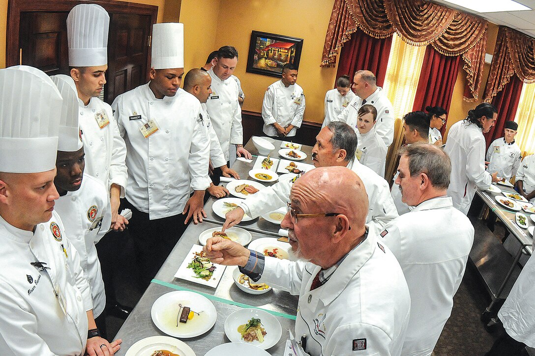 Chefs serving as judges critique the food of service members during a competition