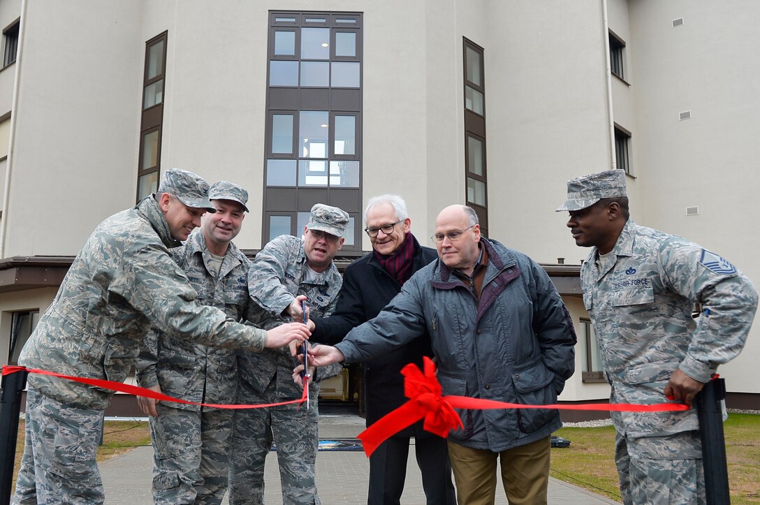 Officials assigned to the 86th Airlift Wing, U.S. Army Corps of Engineers, and the Kaiserslautern State Construction Agency cut a ribbon during a ceremony for a new dormitory building on Ramstein Air Base, Germany, March 7, 2018. The new dorm, 2411, is expected to replace the older dorm 2413. (U.S. Air Force photo by Senior Airman Joshua Magbanua)