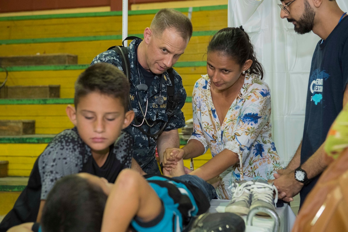 A Navy doctor shows a mother physical therapy exercises in Honduras.