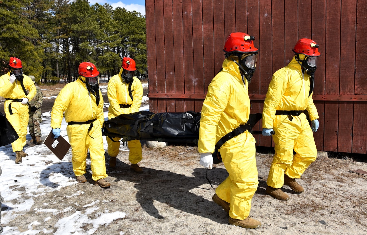 Exercise participants carry a simulated casualty on a stretcher.