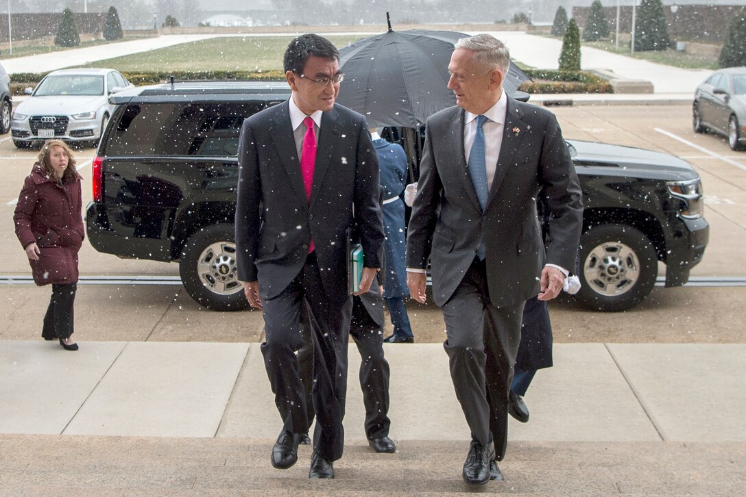 Defense Secretary James N. Mattis shakes hands with a person near a vehicle.