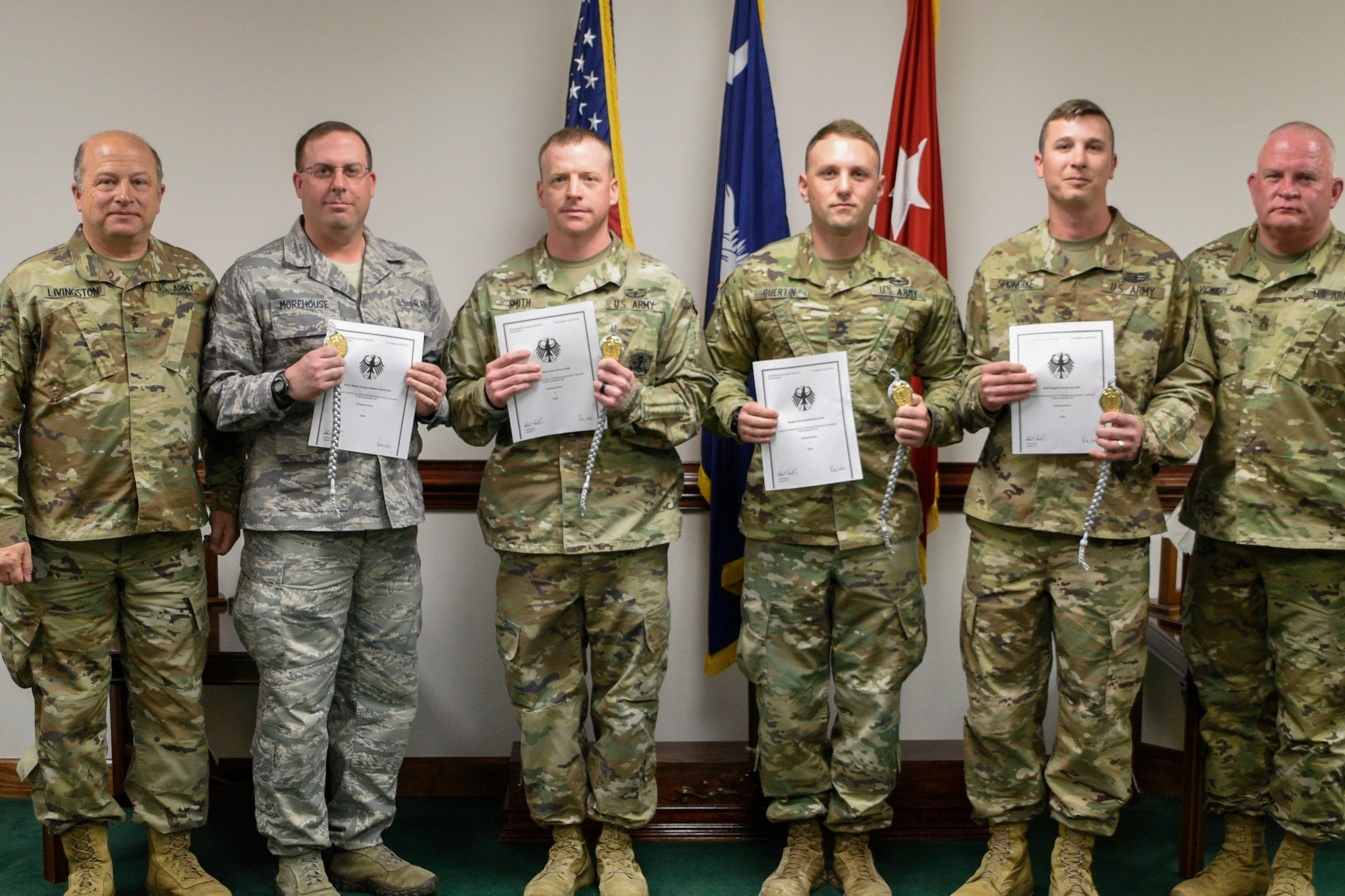 U.S.Army Maj. Gen. Robert E. Livingston Jr., adjutant general for South Carolina and State Command Sgt. Maj. Russel A. Vickery present the Schutzenschnur Badge to Senior Master Sgt. Matthew Morehouse, an intellegence specialist assigned to the South Carolina Air National Guard's 169th Operation Group, for demonstrating profeciency in firing German weapons at a ceremony March 7, 2018 at the Adjutant Generals' building in Columbia S.C. Morehouse and several other service members were chosen to participate in a specialized training opportunity to work with German soldiers. They learned how to fire a German rifle, pistol and machine gun. (U.S. Army National Guard photo by 1st. Lt. Tracci Dorgan)