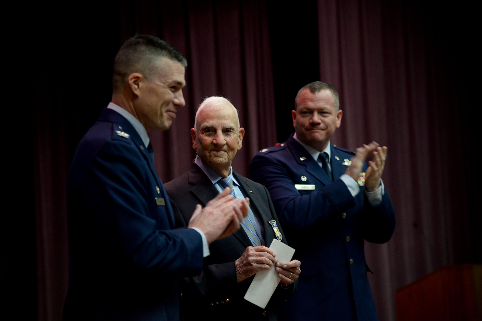 Col. Douglas Gosney, 14th Flying Training Wing commander, and Col. Stanley Lawrie, 14th Operations Group Commander, give retired Col. Carlyle “Smitty” Harris, former Vietnam War prisoner of war, a standing ovation after his graduation speech to Specialized Undergraduate Pilot Training Class 18-06 March 9, 2018, on Columbus Air Force Base, Mississippi. Harris spent 2,871 days in Vietnam as a POW after being shot down April 4, 1965.(U.S. Air Force photo by Airman 1st Class Keith Holcomb)