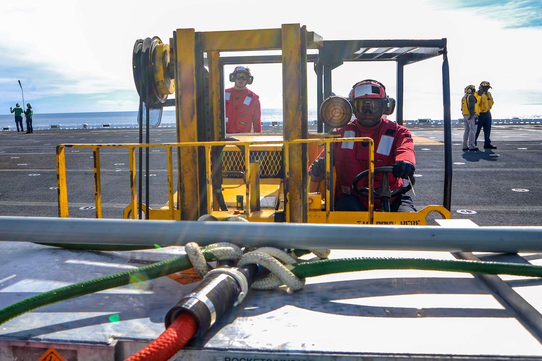 A sailor operates a forklift to repositions ammunition.