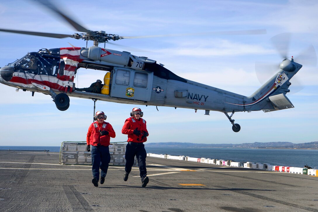 Sailors rush away from a MH-60S Seahawk helicopter.